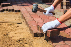 Worker laying red concrete paving blocks in Oshawa